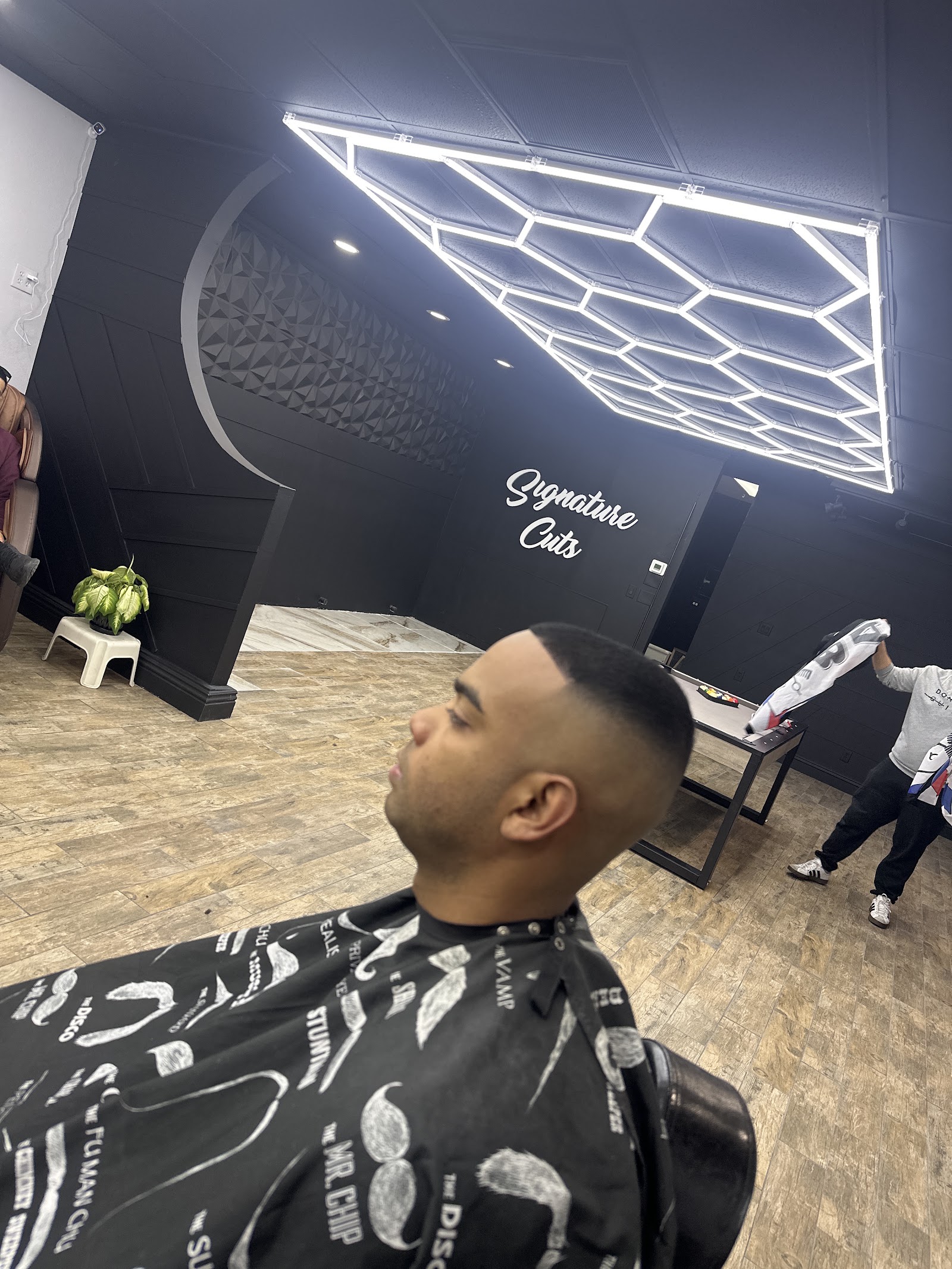 Client with a clean skin fade seated in a barber chair, Signature Cuts interior visible