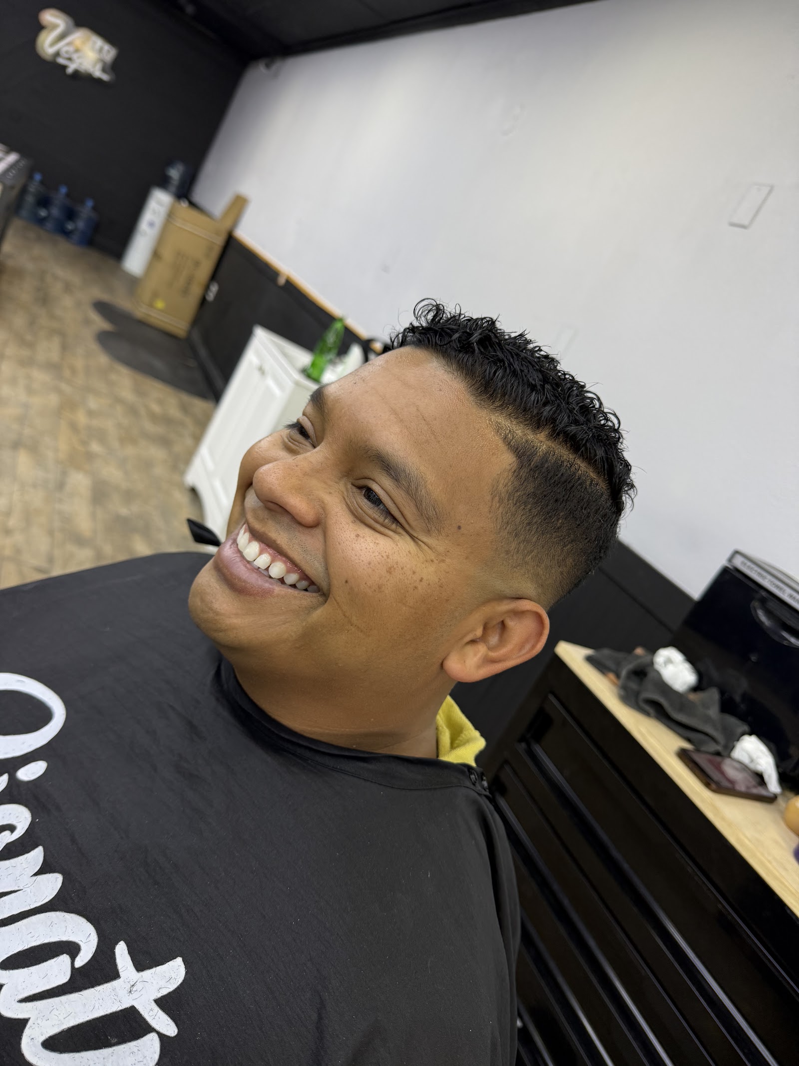 Smiling client with a curly top and skin fade haircut in the barbershop